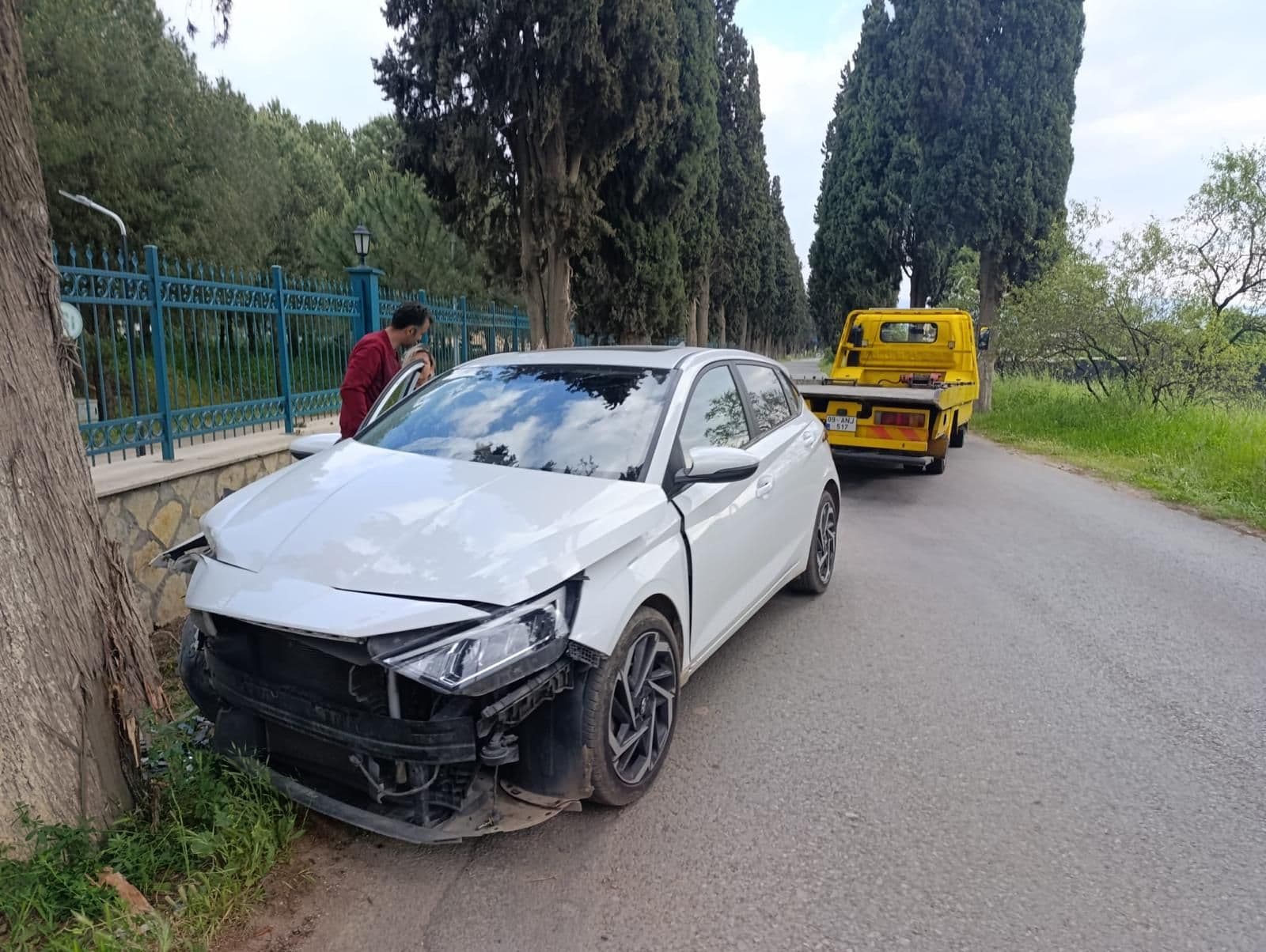 Ön tarafı hasarlı beyaz bir araç, arkada teslim almaya gelen çekici